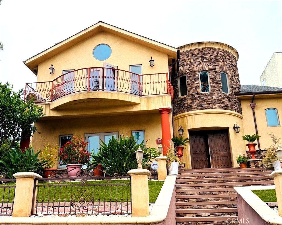 Front exterior of 116 Termino Ave with stone turret, gated courtyard, and terraced landscaping