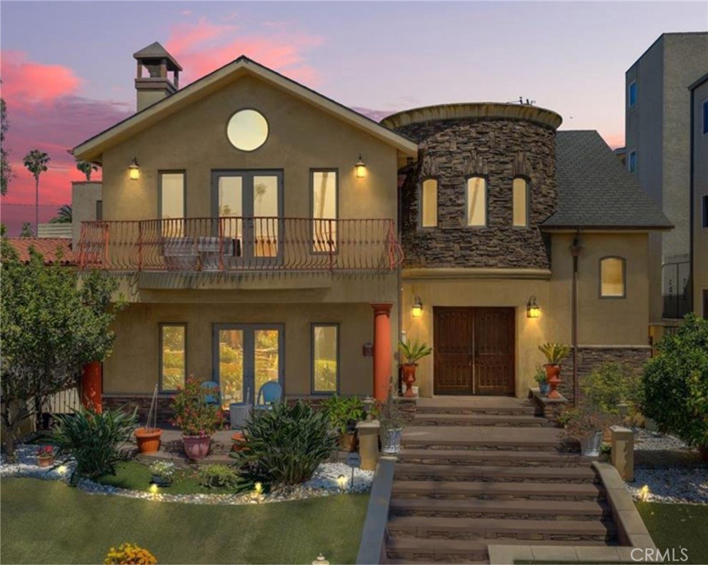 Twilight view of 116 Termino Ave with the stone turret and balcony lit against a sunset sky
